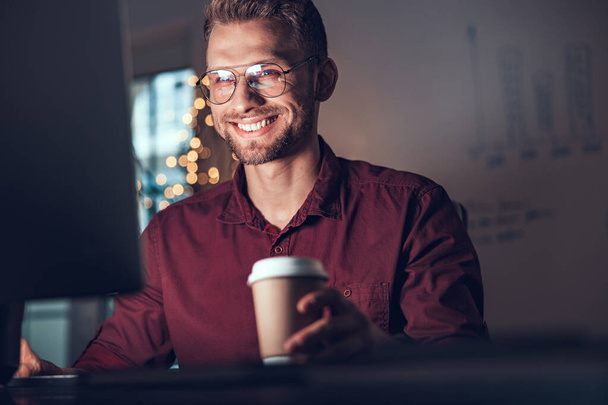 Smiling male worker holding coffee in office - Foto, Bild