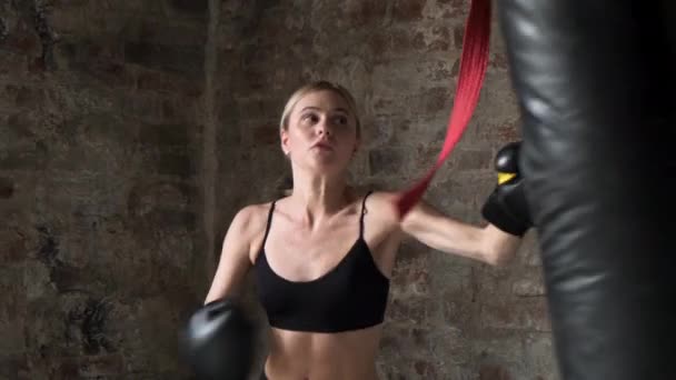 Girl boxing at fitness gym in gloves. Happy woman training box fight in gym. Concentrated fitness woman boxing combat bag in sport club. - Footage, Video