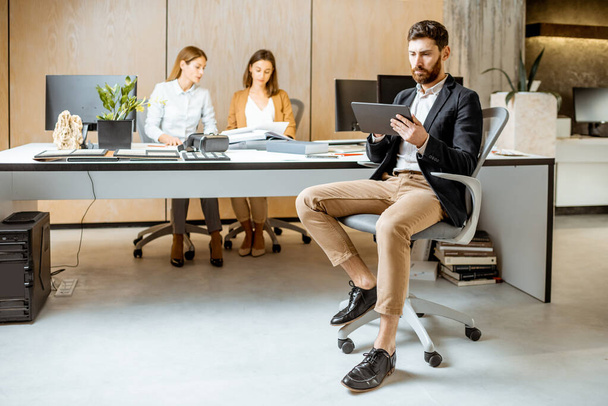 Hombre trabajando en la tableta digital con colegas en la oficina
 - Foto, Imagen