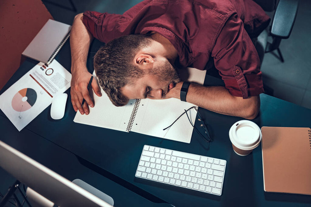 Travailleur masculin fatigué allongé sur la table dans le bureau
 - Photo, image