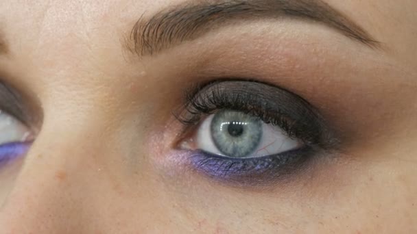 Mooie dure stijlvolle avond make-up rokerige ogen van ongewone grijze en blauwe schaduw van oogschaduw. Mooie vrouwelijke blauwe ogen close-up uitzicht en speciale oog make-up borstel - Video
