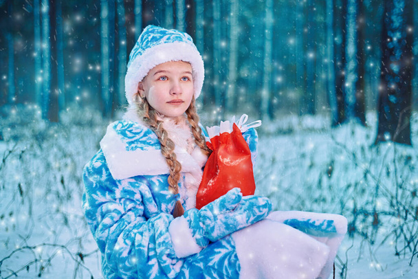 little girl in the woods holds new year's gifts in her hands - 写真・画像
