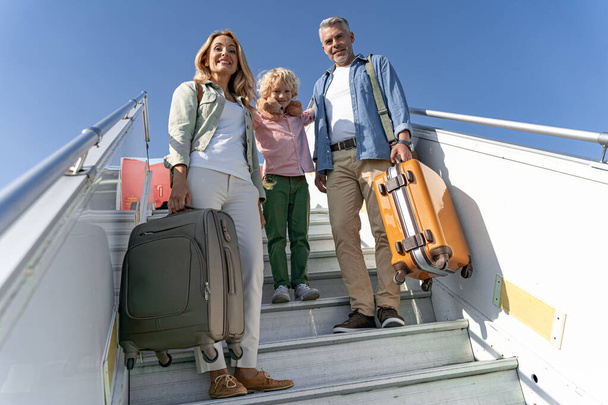 Smiling family with big suitcases near airplane - Фото, зображення