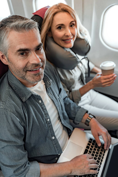 Happy man and woman looking at camera in plane - Foto, imagen