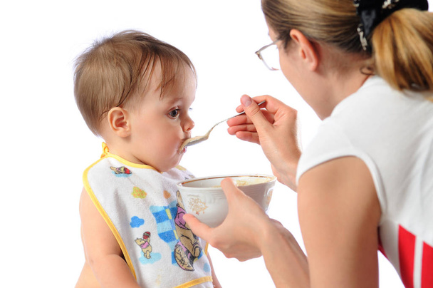 Mother feeds baby girl with spoon - 写真・画像
