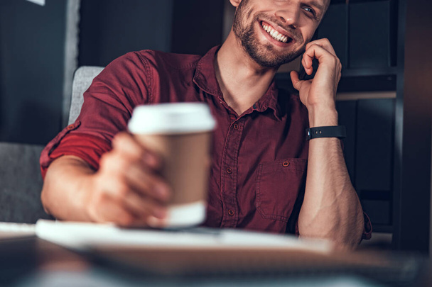 Smiling businessman is talking on smartphone in office - Photo, Image