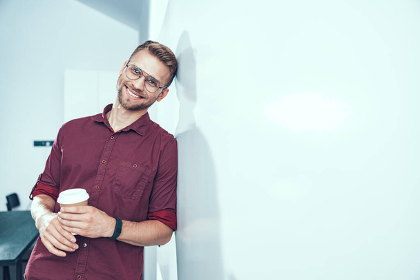 Smiling male worker standing with hot drink - Photo, image