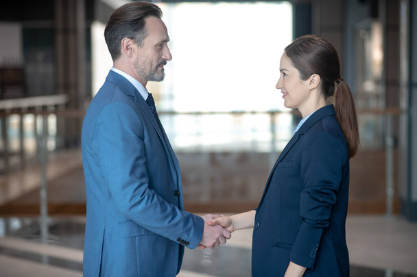 Businessman and businesswoman shaking their hands before serious negotiation - Foto, Bild