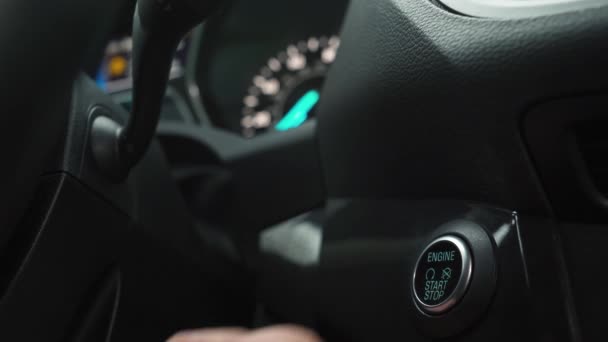 Mano maschile spinge il pulsante di arresto di avvio del motore in un moderno interno auto
 - Filmati, video