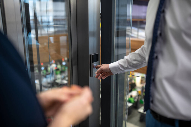Primer plano del hombre de negocios presionando el botón mientras espera el ascensor
 - Foto, imagen
