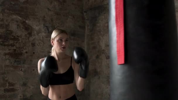 Девочка боксирует в фитнес-зале в перчатках. Счастливая женщина тренируется бокс в спортзале. Концентрированная женская сумка для бокса в спортивном клубе
. - Кадры, видео