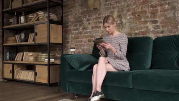 Woman using tablet in home sofa in her living room. Happy female use tablet for texting, reading, watching video and surfing online at home. Lifestyle woman at home concept. - Filmagem, Vídeo