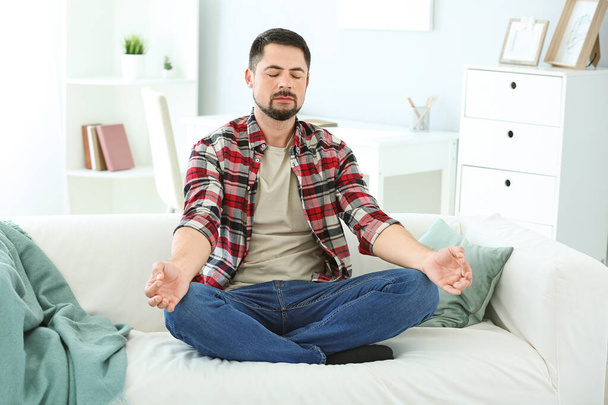 Handsome man meditating at home - Photo, Image