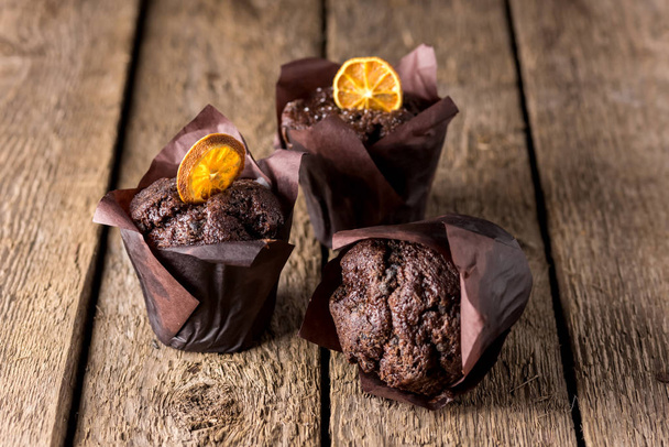Three Chocolate Muffins Decorated With Dried Citrus on Wooden Background Homemade Dessert Horizontal - Foto, immagini