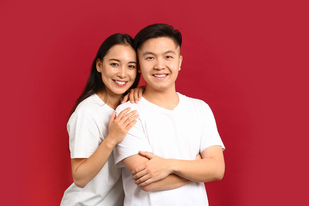 Porträt eines glücklichen jungen asiatischen Paares auf farbigem Hintergrund - Foto, Bild