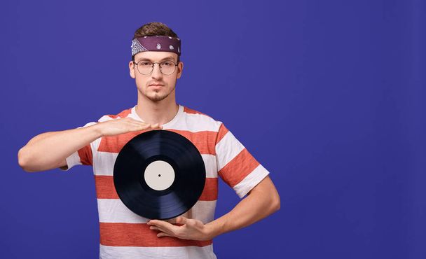Cute guy in glasses holds a music record in his hands. - Foto, imagen