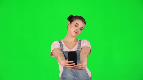 Girl makes selfie on mobile phone then looking photos on green screen - Felvétel, videó