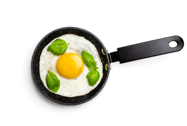 Fried egg with basil leaf on small pan isolated on white  - Φωτογραφία, εικόνα
