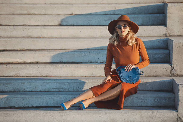 Portrait of fashionable young woman sitting on steps outdoors - Photo, Image