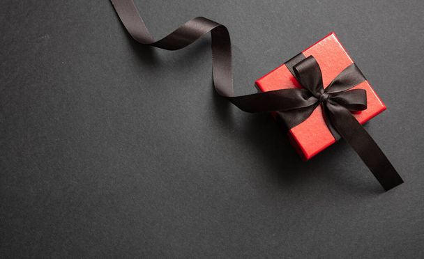 Gift box with black ribbon against black background, Black Friday concept. - Foto, afbeelding