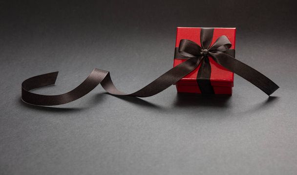 Подарочная коробка с черной лентой на черном фоне, концепция Черной пятницы
. - Фото, изображение