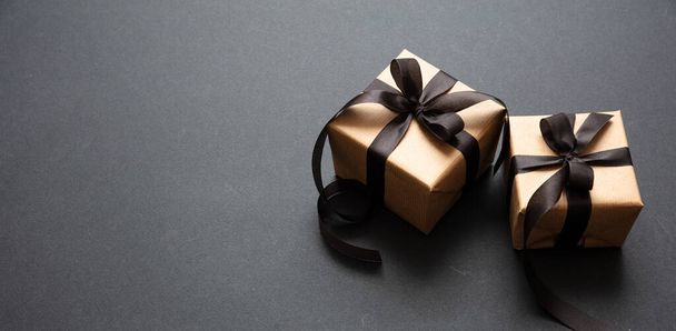 Gifts with black ribbon against black background, Black Friday concept. - Фото, изображение