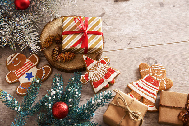 fir takken, Kerstmis peperkoek koekjes, geschenken en decoraties op een lichte houten achtergrond. - Foto, afbeelding