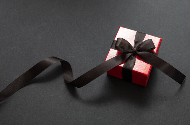 Gift box with black ribbon against black background, Black Friday concept. - Photo, Image