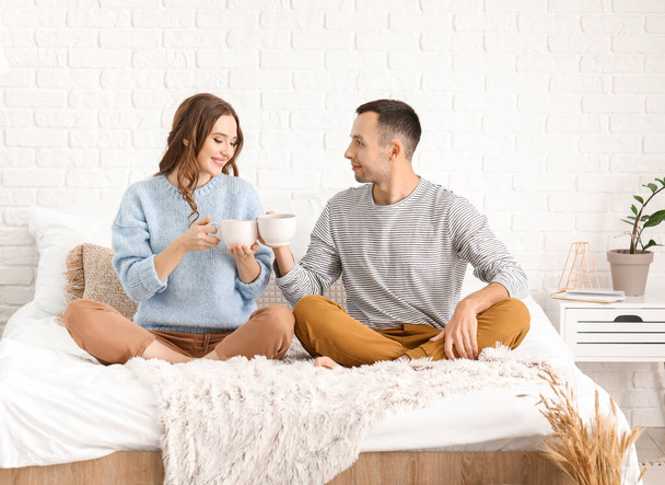 Hermosa pareja joven bebiendo té en la cama en casa
 - Foto, Imagen