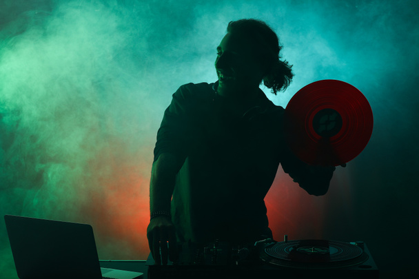 Silueta de dj masculino tocando música en discoteca
 - Foto, imagen