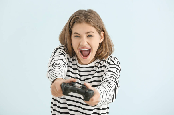 Emotionele tiener meisje met spel pad op lichte achtergrond - Foto, afbeelding
