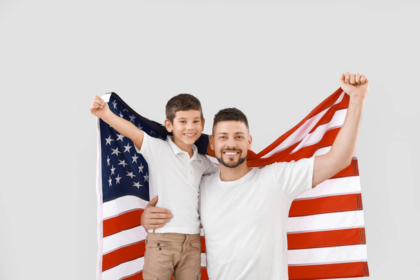 Man and his son with USA flag on light background. Memorial Day celebration - Фото, изображение