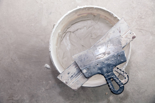 İnşaat kovasında dekoratif çimento sıva ve mala sıva için hazır. Spatula ve bir kova beyaz macun. Üst görünüm - Fotoğraf, Görsel