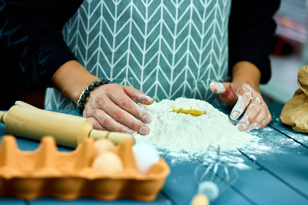Man formt den Teig auf einer bemehlten Fläche und knetet ihn mit den Händen. Hand eines Bäckers, der Teig knetet. Prozessvorbereitung hausgemachtes Gebäck. Kochen von Pasta, Spaghetti, Pizza-Food-Konzept. - Foto, Bild