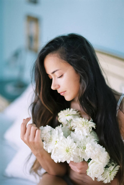 Morning portrait of young brunette woman with white flowers bouq - Foto, Imagen