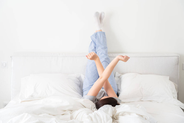 Frau streckt sich im Bett, Beine hoch im Schlafzimmer - Foto, Bild