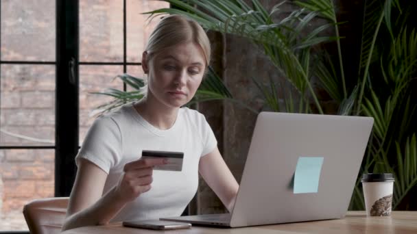 Красива дівчина робить онлайн-платежі, тримаючи банківську картку, використовуючи сучасний ноутбук вдома сидячи і посміхаючись. Фінанси, покупки в Інтернеті та молодіжна концепція
. - Кадри, відео