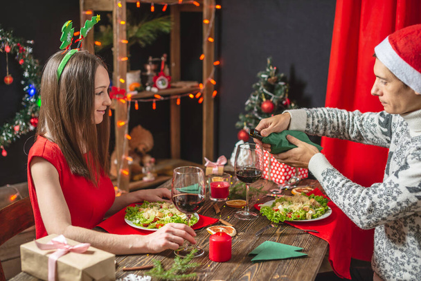 Casal de amantes passam a noite jantando e bebendo vinho de óculos nas decorações de Natal na véspera de Ano Novo
. - Foto, Imagem