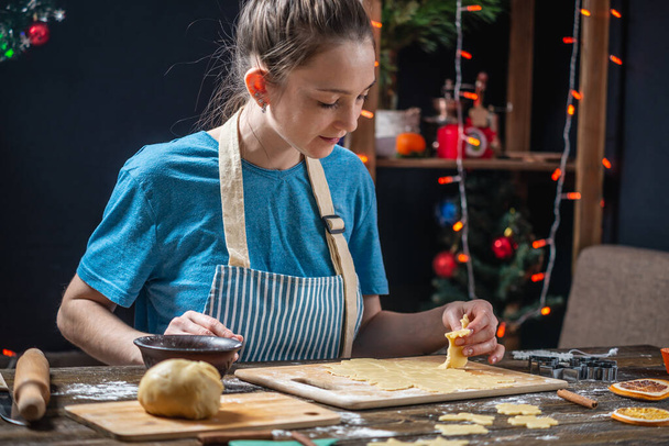 Jeune femme au foyer fait de la pâte pour cuisiner du pain d'épice festif. Ambiance chaleureuse dans la soirée le soir de Noël
 - Photo, image
