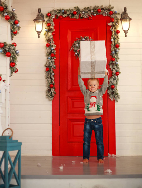 Little boy child with gift in yard at home in Christmas decor - Фото, изображение