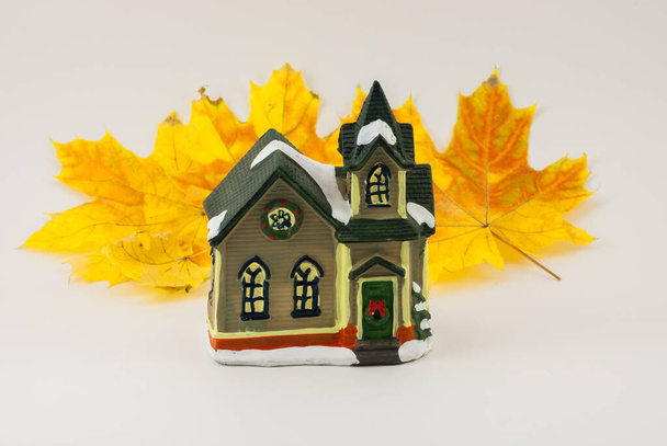 Prachtige creatieve herfstcompositie. Een klein speelgoedhuisje. gedroogde heldere bladeren, close-up - Foto, afbeelding