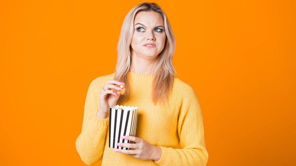 Young cheerful woman watching a blockbuster and eating popcorn. - Fotoğraf, Görsel