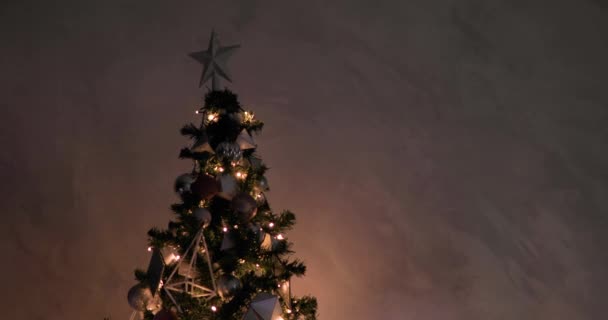 Χριστουγεννιάτικο δέντρο με φωτεινή γιρλάντα, διακοσμημένο ασημένιο αστέρι στην κορυφή και μπάλες. - Πλάνα, βίντεο