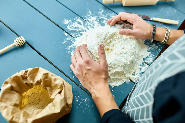 Man forming the dough on a floured surface and kneading it with his hands. Hand of baker kneading dough. Process preparation homemade pastry. Cooking pasta, spaghetti, pizza food concept. - Fotó, kép
