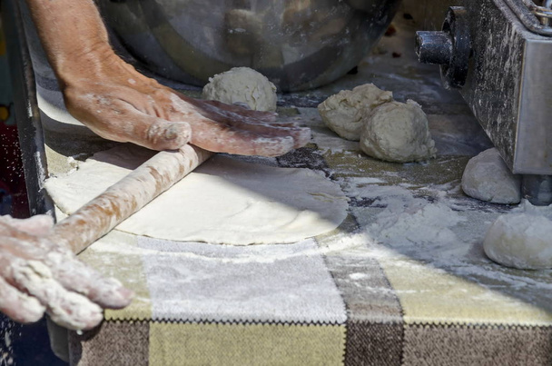 Sofia, Bulgaria - September 15, 2019: Technology for the manual preparation of  dough for pizza with a rolling pin and flour, Sofia, Bulgaria. Visit in place.  - Фото, изображение