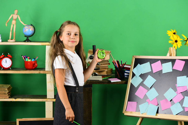 Kid and school supplies on green wall background - Фото, зображення
