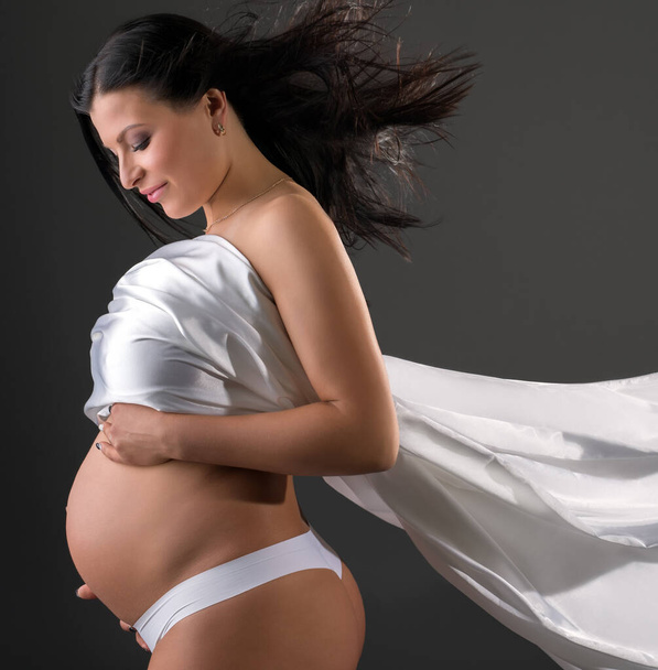 Sensual pregnant woman poses with fluttering cloth - Photo, image