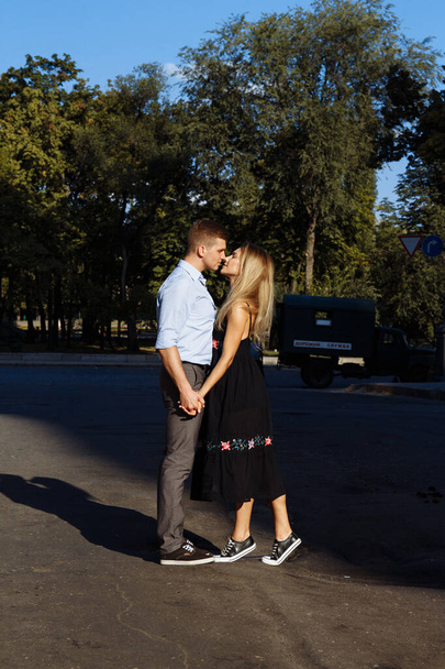 щаслива пара обіймає і стоїть перед містом. темний фон, сонце світить на коханців
 - Фото, зображення
