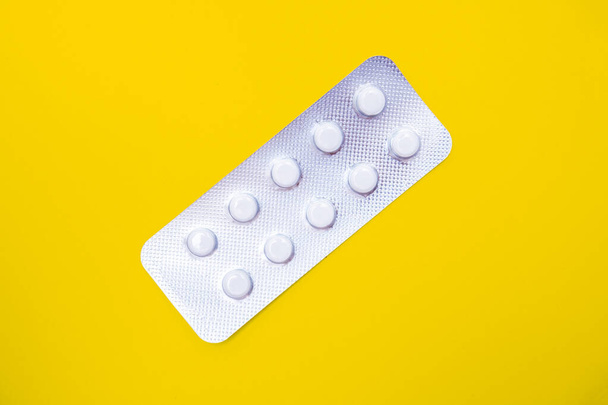 A blister pack of statins, pills tablets for lowering cholesterol on yellow background, prevention and treatment of atherosclerosis and heart disease concept, copy space - Foto, afbeelding