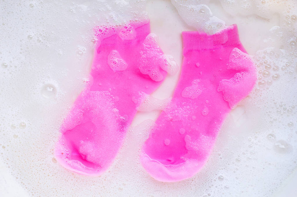 粉末洗剤水溶解に浸漬ピンクの靴下。発射 - 写真・画像